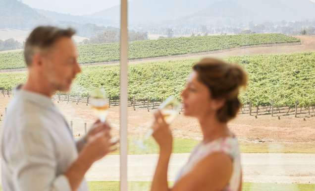 Couple enjoying wine with scenic views across Logan Wines vineyard in Apple Tree Flat near Mudgee.
