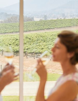 Couple enjoying wine with scenic views across Logan Wines vineyard in Apple Tree Flat near Mudgee.