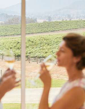 Couple enjoying wine with scenic views across Logan Wines vineyard in Apple Tree Flat near Mudgee.