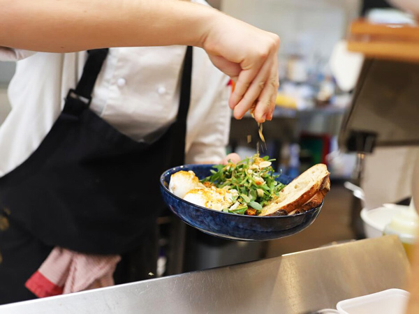a chef sprinkling some seasoning on a dish at Hey days, Townsville