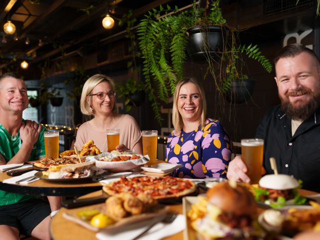 people sitting and smiling while enjoying food and drinks at Milton Common, Brisbane brewery