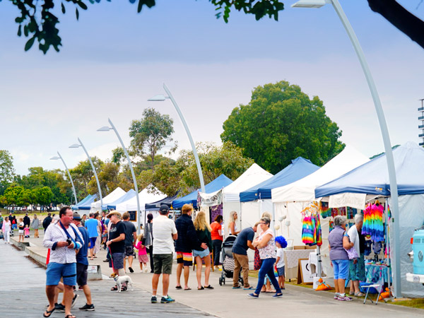 a crowd of people strolling along the stalls at Tweed Harbourside Market