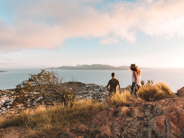 a couple hiking to the top of Castle Hill at sunset