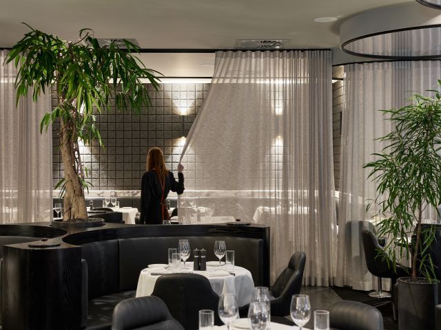 a woman sliding the curtains inside the dining room at Fatcow, Fortitude Valley