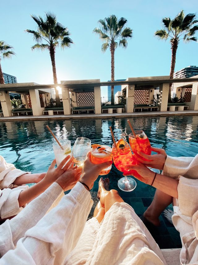 hands holding poolside cocktails at Hellenika, Fortitude Valley