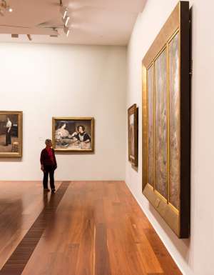 a man looking at artworks on the wall inside The Ian Potter Centre: NGV Australia, CBD