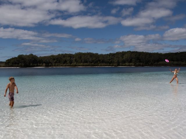 kids playing with a frisbee in lake mckenzie on k'gari fraser island