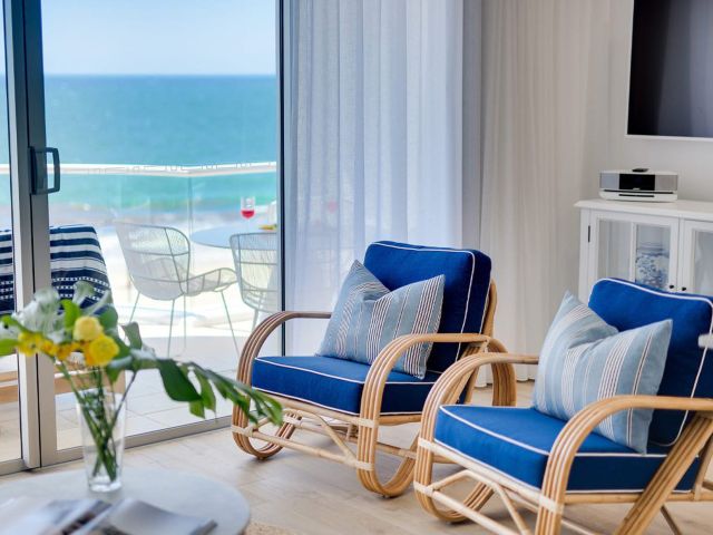 blue chairs beside a window with beach views at Tingirana Noosa
