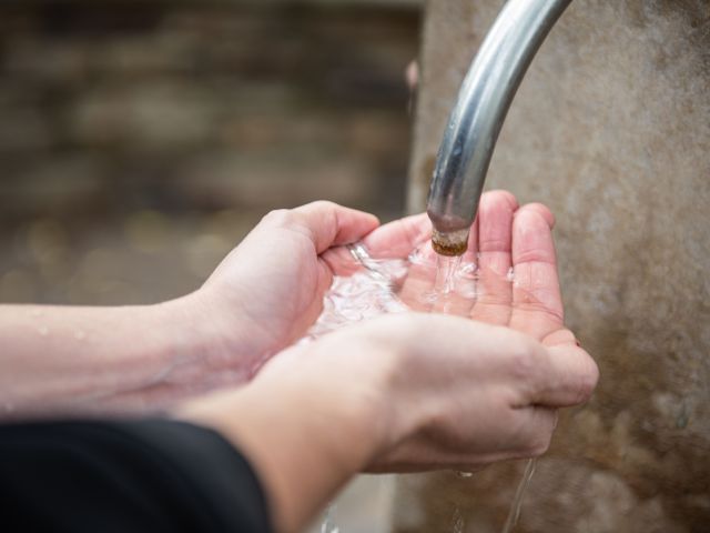 a person cupping their hands to collect water from tap