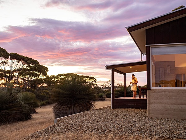 A couple watches the sun set from the deck ar Ecopia Retreat on Kangaroo Island