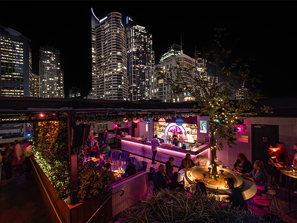A rooftop bar with lots of floral decorations and pops of neon.