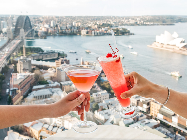Two people clinking cocktails at Blu Bar on 36 is perched high above the harbour with uninterrupted views of Sydney Harbour and the Opera House.