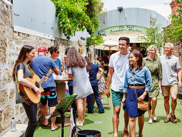 a couple passing by a local musician performing at Fremantle Markets, Perth