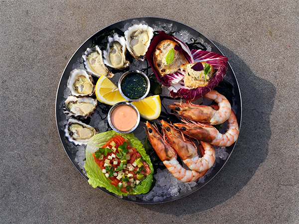 A colourful seafood platter with oysters, prawns, mussels and salsa.