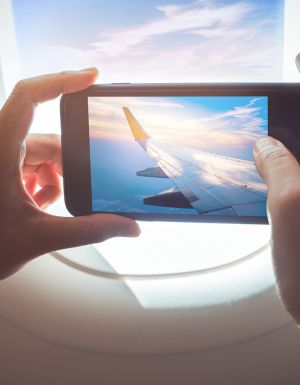 person taking a photo out of the plane window while in flight