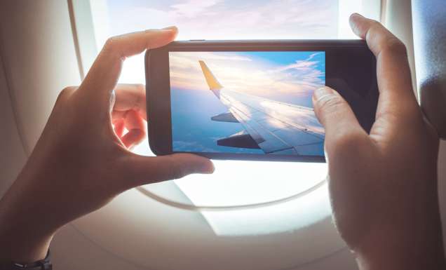 person taking a photo out of the plane window while in flight
