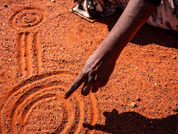 An-angu guide finger painting in the sand
