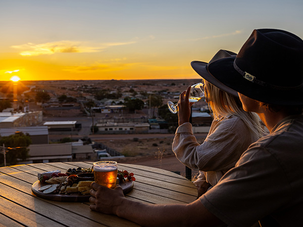 two people drinking at a pub in coober pedy during sunset
