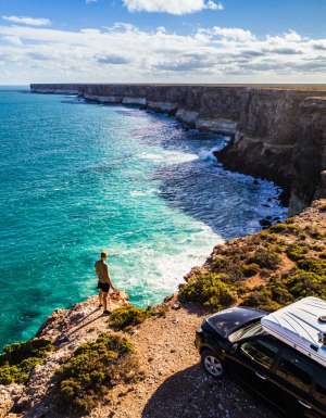 Aerial view of car parked with camper and young man overlooking the Great Australian Bight. Captured while crossing the Nullarbor.