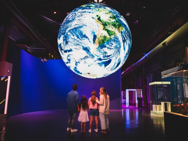 a family admiring the planet Earth display inside Newcastle Museum Planetarium