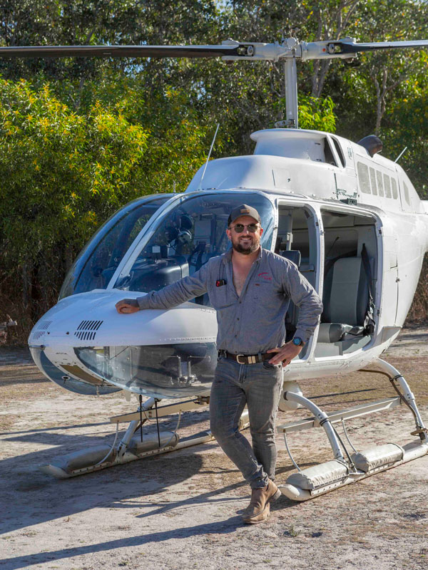 pilot Nathan Summerfield posing beside a helicopter, Cape York Wilderness Adventure