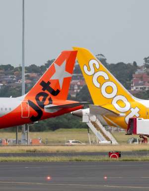 A Jetstar Airbus A321-251NX plane, registration VH-OYP, taxiing at Sydney Kingsford Smith Airport for departure as flight JQ37 to Denpasar. She is passing a Scoot Boeing B787-9 plane, registration 9V-OJC