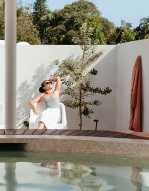 A woman relaxes beside the baths at Byron Bay Bathhouse
