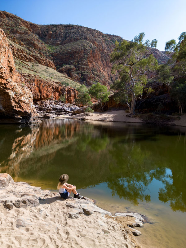 a woman sitting on a rock at Ormiston Gorge