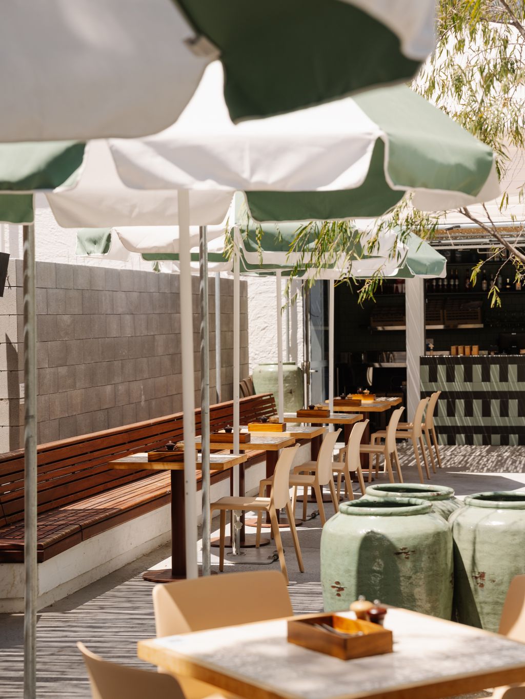 Green and white striped umbrellas in an alfresco dining area