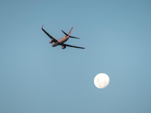 A Virgin Australia plan4e flying with the moon in the background