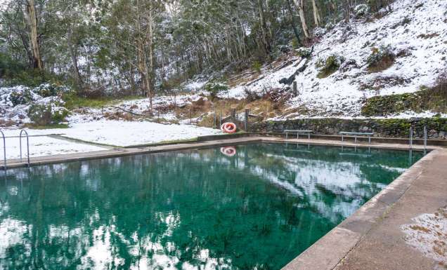 Hot spring pool with crystal clear water and snow covered ground nearby. Yarrangobilly thermal pool, Australia