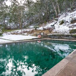 Hot spring pool with crystal clear water and snow covered ground nearby. Yarrangobilly thermal pool, Australia