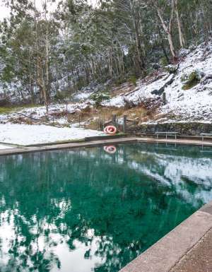 Hot spring pool with crystal clear water and snow covered ground nearby. Yarrangobilly thermal pool, Australia