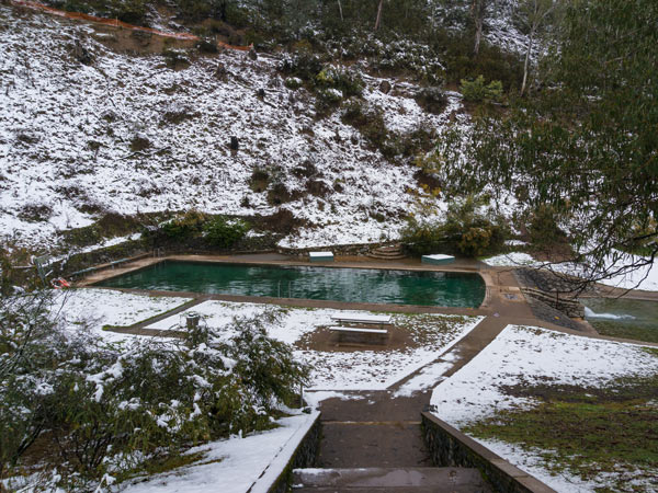 Outdoor swimming pool with winter landscape and snow. Yarrangobilly hot spring pool, Australia
