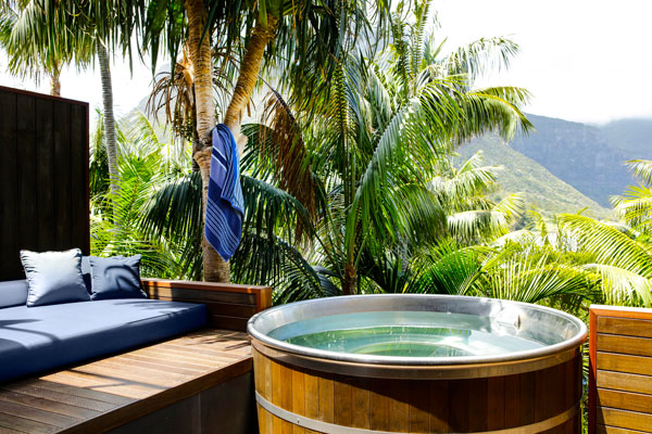 a hot tub surrounded by kentia palms and daybeds at Capella Lodge, Lord Howe Island