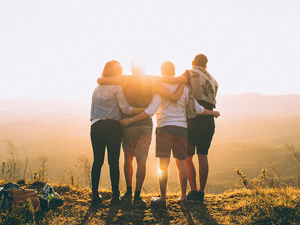 four friends with arms around each other at a lookout