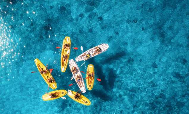 Aerial view of yellow kayaks in blue sea at sunset in summer
