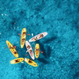 Aerial view of yellow kayaks in blue sea at sunset in summer