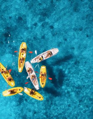 Aerial view of yellow kayaks in blue sea at sunset in summer