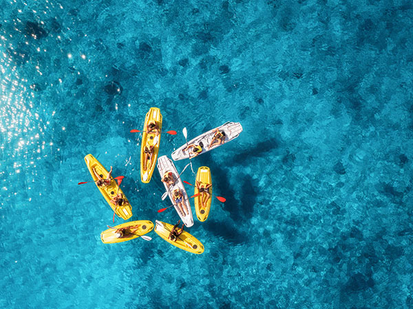 Aerial view of yellow kayaks in blue sea at sunset in summer