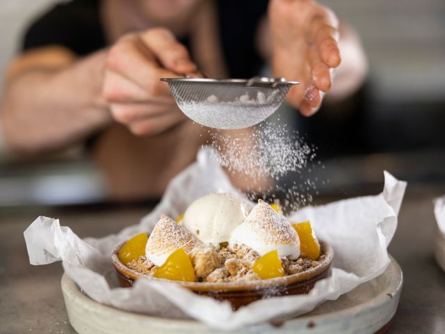 sprinkling powdered sugar on top of a pastry at Henri Marc, Penrith