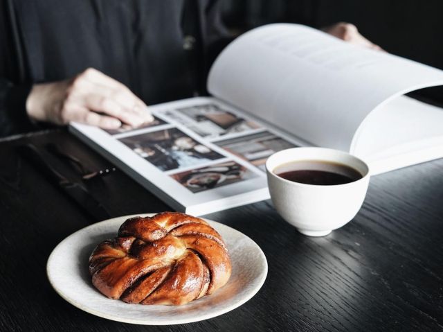 browsing a book with coffee and bread on the table at Edition Roasters