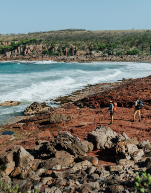 Two people walking on the rocky shoreline near the ocean. Light to Light walk