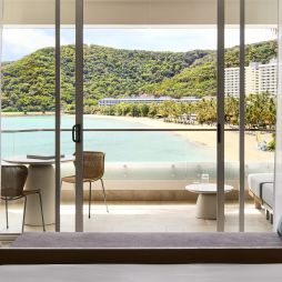 A modern hotel room overlooking a tropical beach