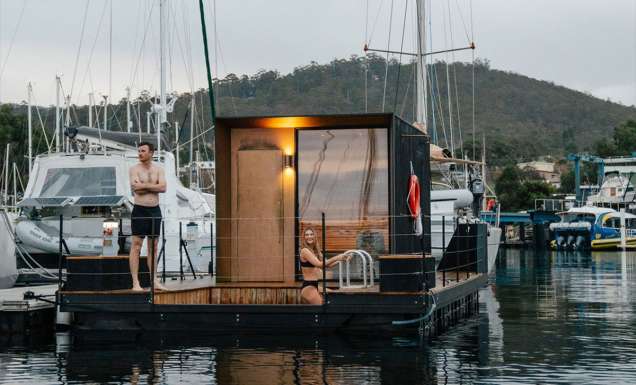 A man and woman standing on a floating sauna.