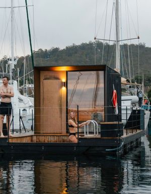 A man and woman standing on a floating sauna.
