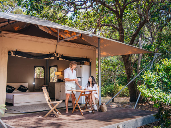 a couple eating breakfast outside their glamping tent at Minjerribah Camping