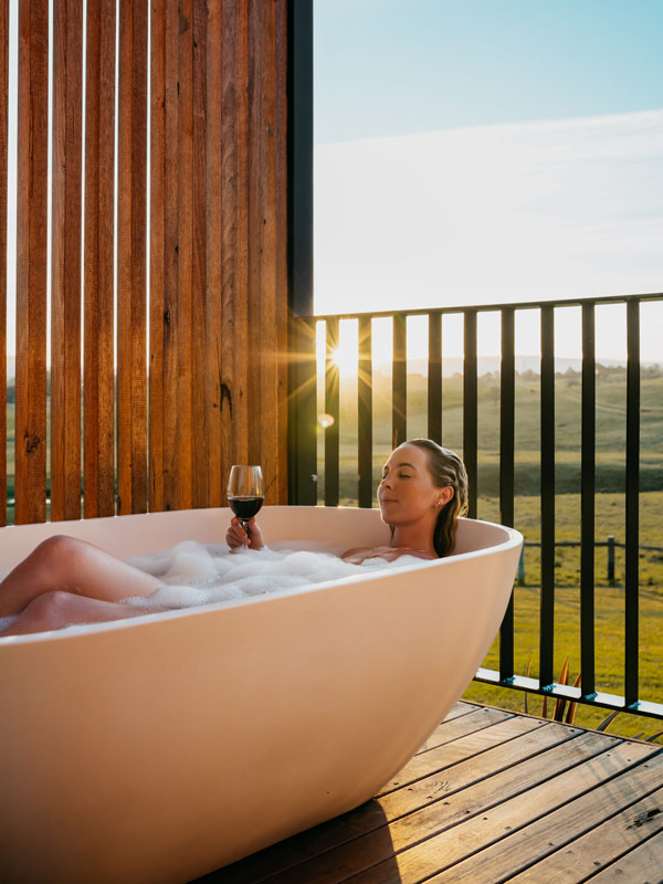 a woman soaking in a tub with wine in hand at Cupitt’s Estate inShoalhaven