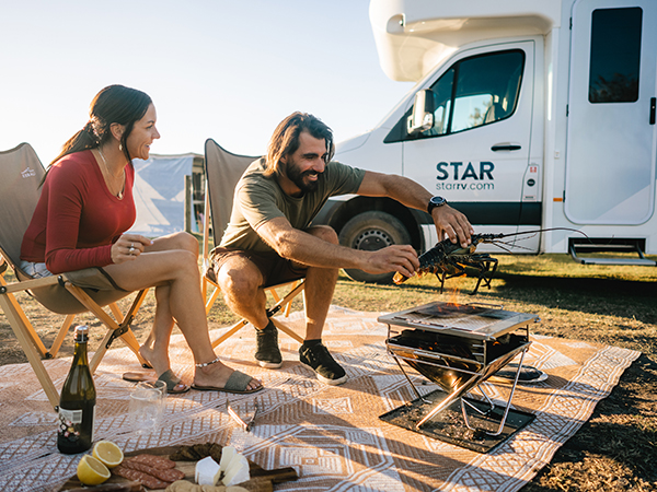 A couple having a picnic beside Star RV Motorhomes.