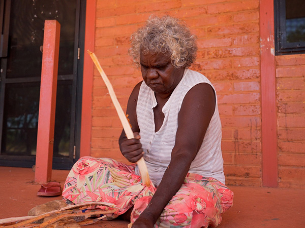 an Aboriginal artist weaving a dilly bag in Barramundi Lodge